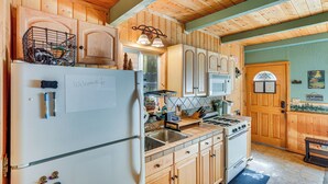 Eine Küche mit Holzschränken, einem Kühlschrank, einem Herd und einem Spülbecken.