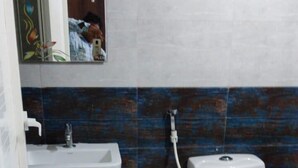 A bathroom with a white sink, a toilet, and a mirror with a decorative frame. - PPH Living Bhimas (Tada)