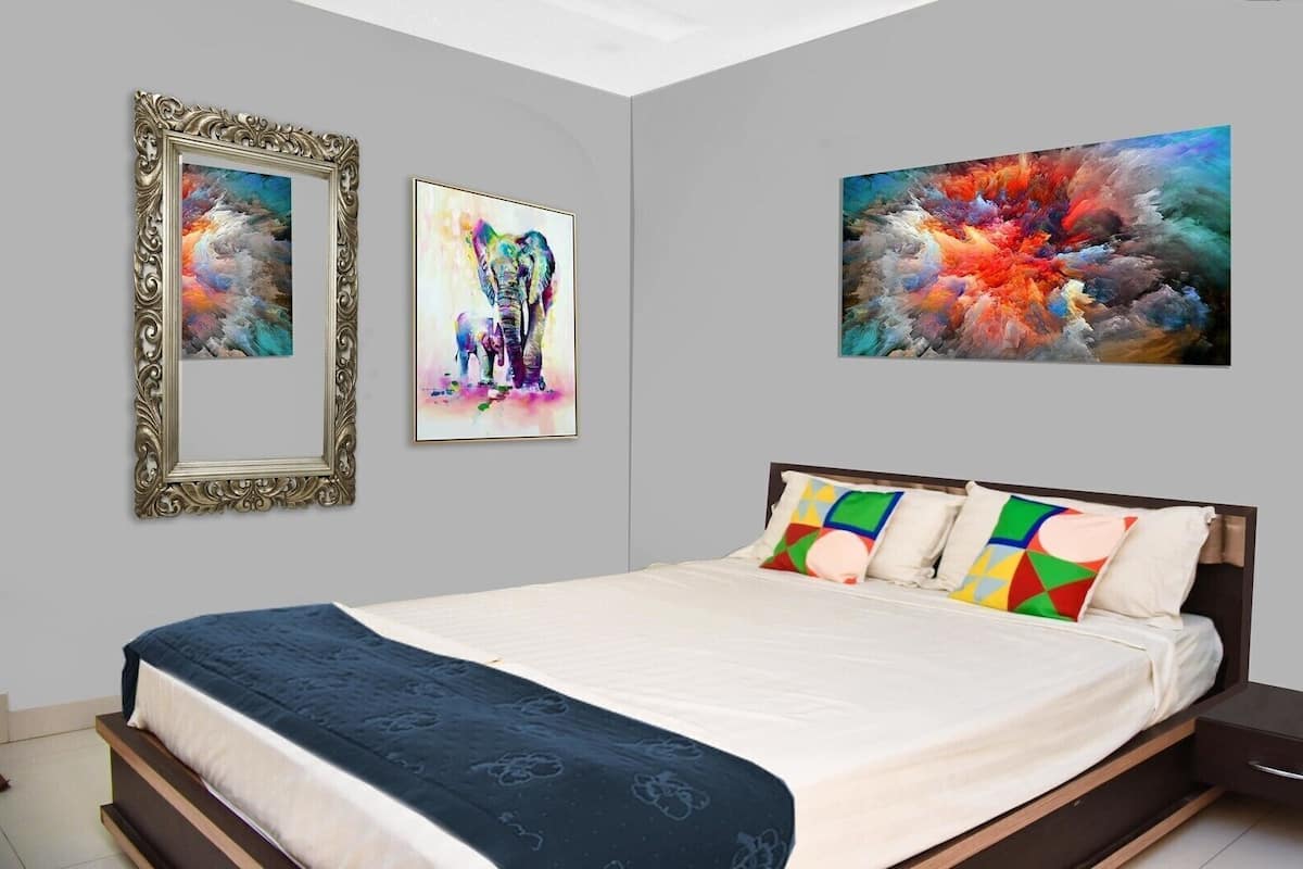A bedroom with a bed, pillows, a nightstand, and two framed artworks on the wall.