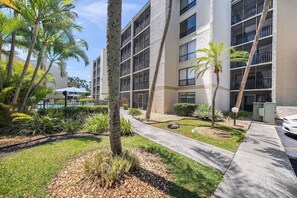 A multi-story building with a pool area, palm trees, and a well-maintained garden. - Peaceful Bayfront Retreat at Siesta Key's Bay Oaks (Siesta Key)