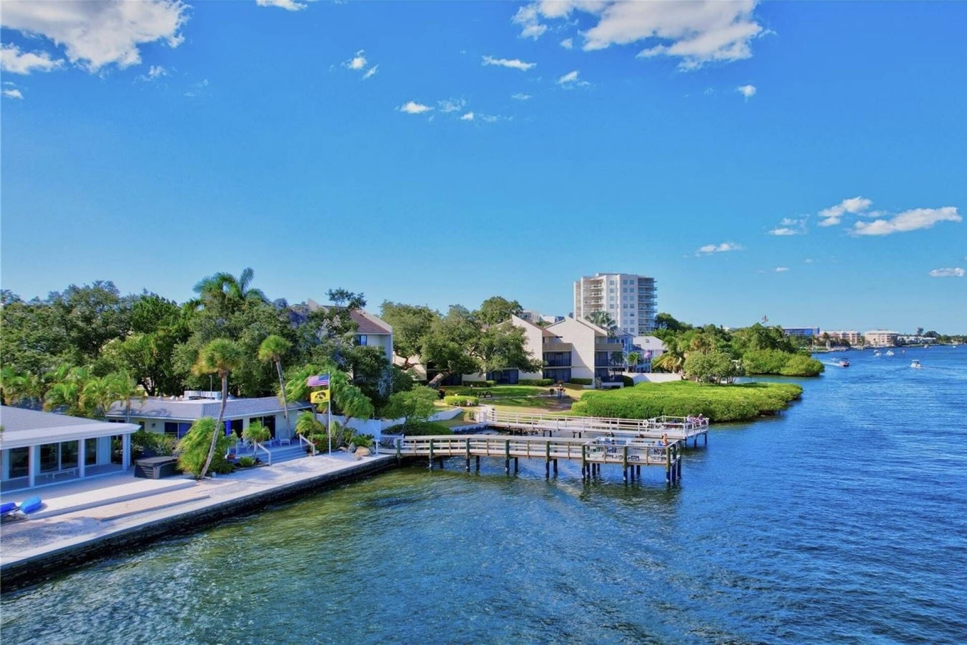 Ein Anwesen am Wasser mit Anlegesteg, ein Gebäude mit Flachdach und strahlend blauem Himmel.