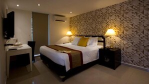 Een moderne hotelkamer met een groot bed, twee bedlampen, een flatscreen televisie en een bureau met stoel.