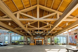 A spacious lobby with a high wooden ceiling and stone walls, large windows, and a view of the outdoors. - Westgate 4201 (Park City)