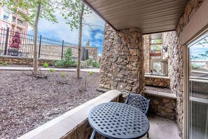 Une terrasse extérieure avec des murs en pierre, une table en métal et des chaises.