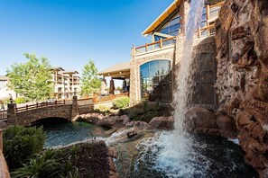 Un hôtel doté d’une cascade, d’un pont en pierre et d’un espace piscine.