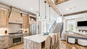 A spacious kitchen with wooden cabinets, a central island, and a dining area with chairs.