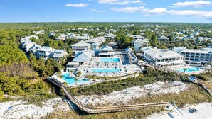 An aerial view of a resort with multiple buildings, a large swimming pool, and a beach area.