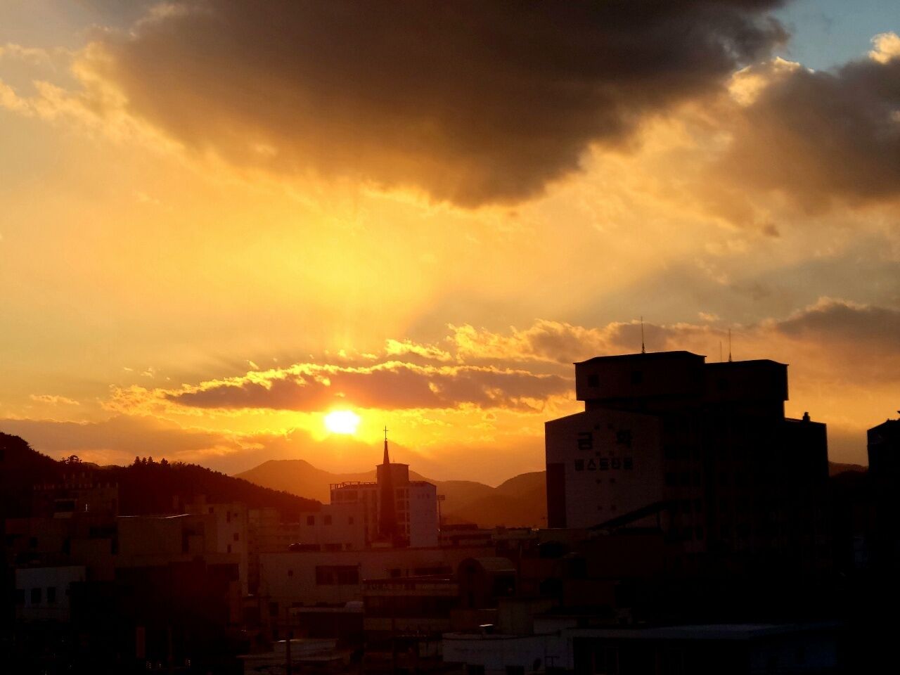 A cityscape at sunset with buildings silhouetted against the sky.