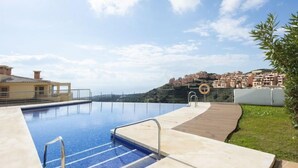 Une piscine dotée d’une terrasse en bois et offrant une vue sur une ville côtière.