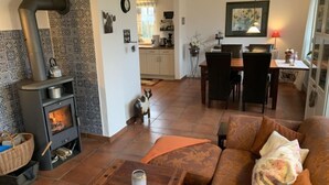 Ein gemütliches Wohnzimmer mit Kamin, einem Essbereich und einer Küche im Hintergrund.