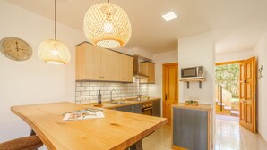 Et moderne køkken med træskabe, en central ø, hængende lamper og en mikroovn på væggen.