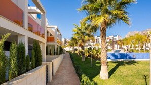 A modern hotel corridor with a pathway, palm trees, and a pool area. - Alegría Village by Interhome (Benidorm)