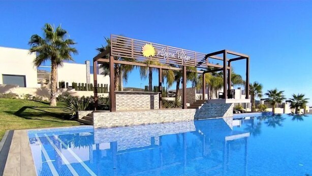 A clear blue pool with a wooden pergola and steps leading to a lounge area, surrounded by palm trees and a clear sky. - Alegría Village by Interhome (Benidorm)