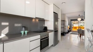 A modern kitchen with white cabinets, a stainless steel refrigerator, and a black stove. - Alegría Village by Interhome (Benidorm)