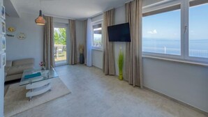 Una sala de estar moderna con un sofá, una mesa de centro de vidrio y un televisor montado en la pared.