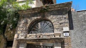 Un edificio in pietra con un cancello in ferro battuto e un cartello che riporta la scritta "ROMITAAGGS".
