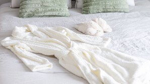 A neatly made bed with white bedding and two pillows, one green and one gray, in a room with a wall-mounted artwork above. - Modern Living with an Outdoor Oasis (Scottsdale)
