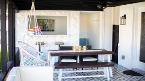 A dining area with a white cushioned bench, a wooden table, and a hanging chair. - Modern Living with an Outdoor Oasis (Scottsdale)