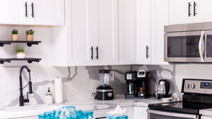 A modern kitchen with white cabinets, a central island with bar stools, a microwave, and a coffee maker. - Modern Living with an Outdoor Oasis (Scottsdale)