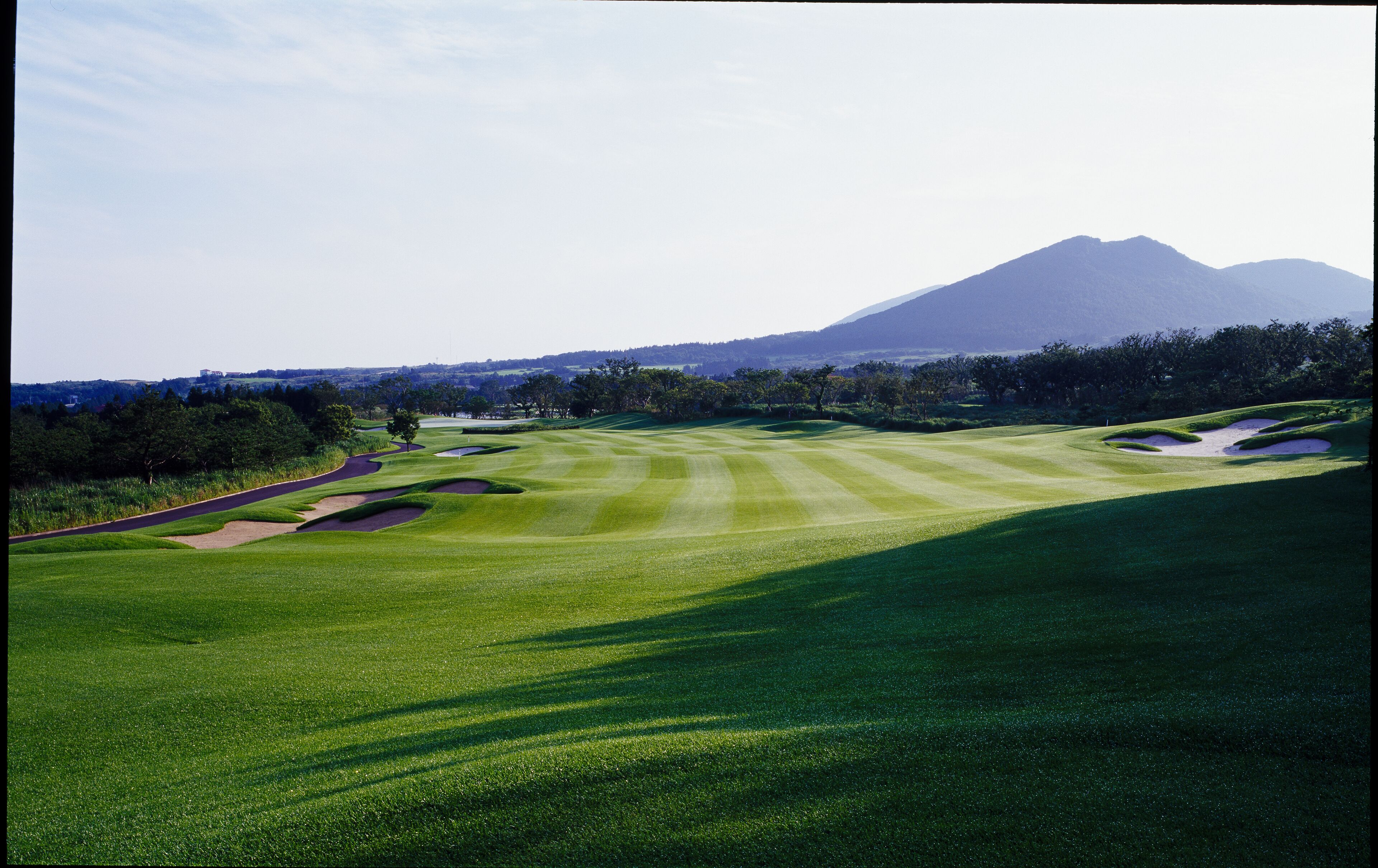 Ein Golfplatz mit einem Berg im Hintergrund.
