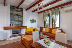 A living room with a fireplace, a sofa set, a wooden coffee table, and a dining table.