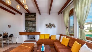 A modern living room with a sectional sofa, a wooden coffee table, and a fireplace. - Evilion Villa (gennadi)