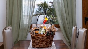 A wicker basket filled with food items on a table with a view of a plant through sheer curtains. - Evilion Villa (gennadi)