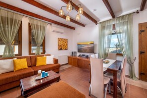 Ein modernes Wohnzimmer mit Sofa, Couchtisch, Fernseher und Essbereich.