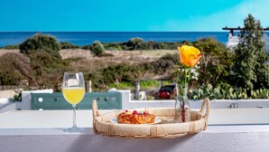 A wicker basket with a croissant and a glass of yellow beverage on a balcony with a view of the sea. - Evilion Villa (gennadi)