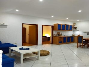 Een ruimtelijk ingerichte leefruimte met kitchenette, eethoek en slaapkamer.