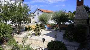 A courtyard with a hammock, a stone fountain, and a stone chimney. - Apartment Barbara (Vir)