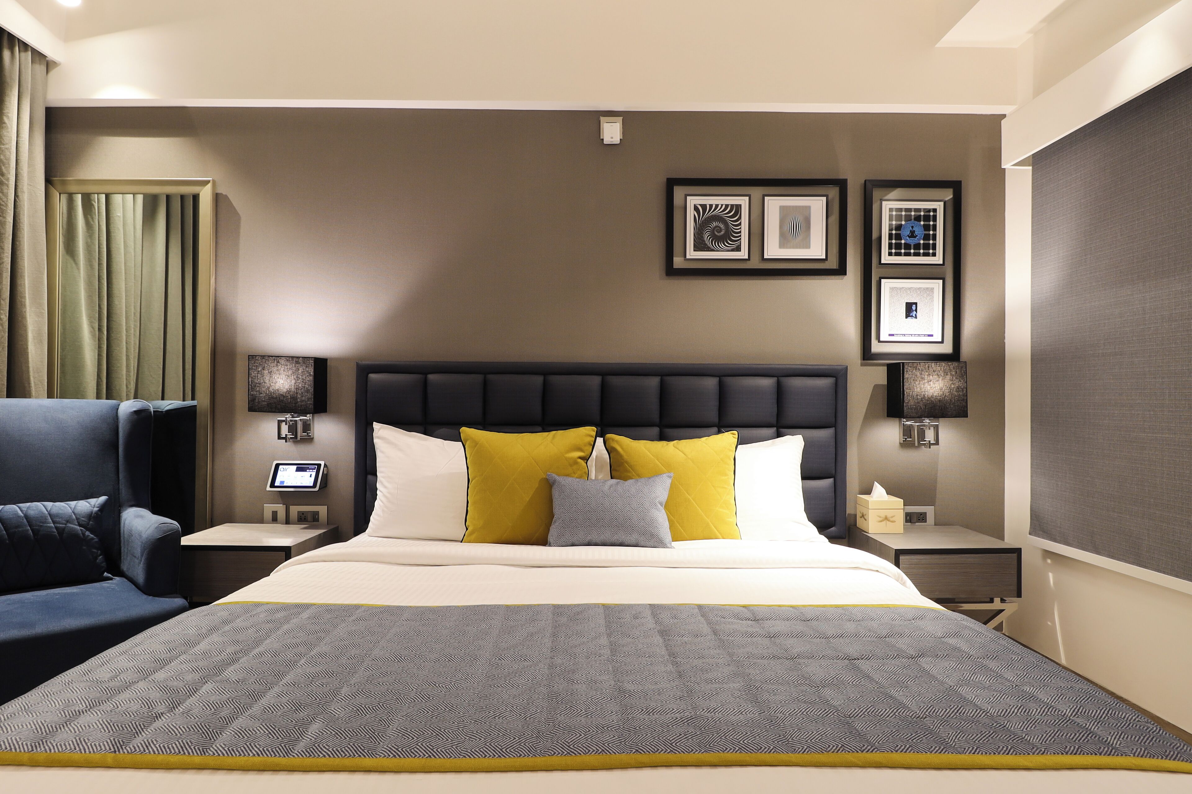 Ein Hotelzimmer mit einem großen Bett, einem Nachttisch mit Lampe, einem Sessel und einem Bild an der Wand.