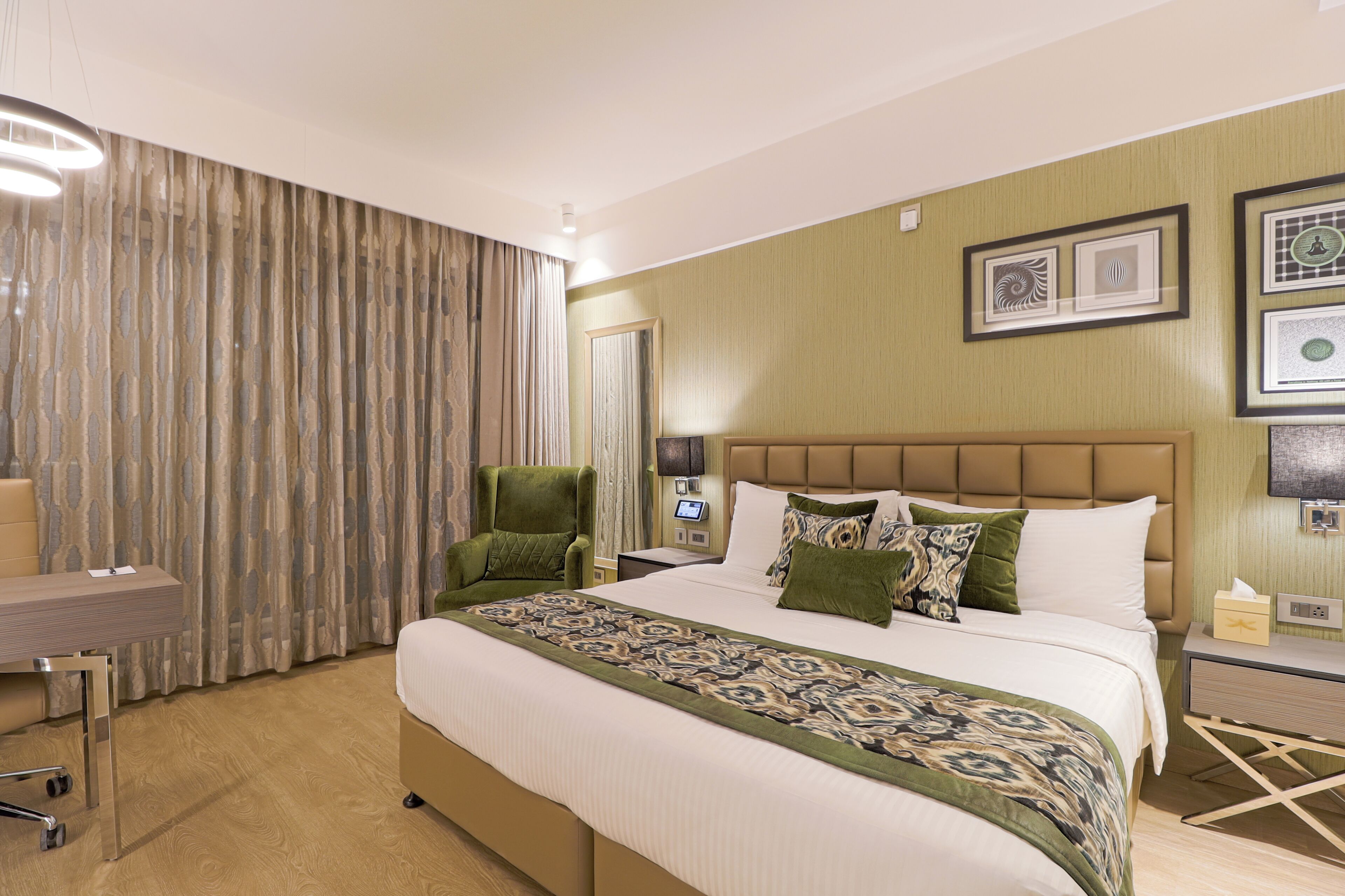 A hotel room with a large bed, a desk, a chair, and a television.