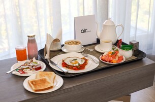 A breakfast tray with toast, eggs, fruit, and beverages on a hotel table.