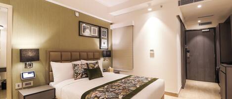 A hotel room with a large bed, bedside tables, a flat-screen TV, and a control panel.