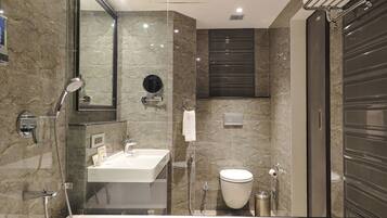 Un baño moderno con ducha de vidrio, lavamanos blanco y retrete.