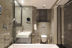 Un baño moderno con ducha de vidrio, lavamanos blanco y retrete.