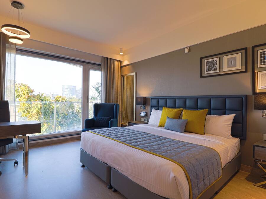 A modern hotel room with a large bed, a desk, and a chair.