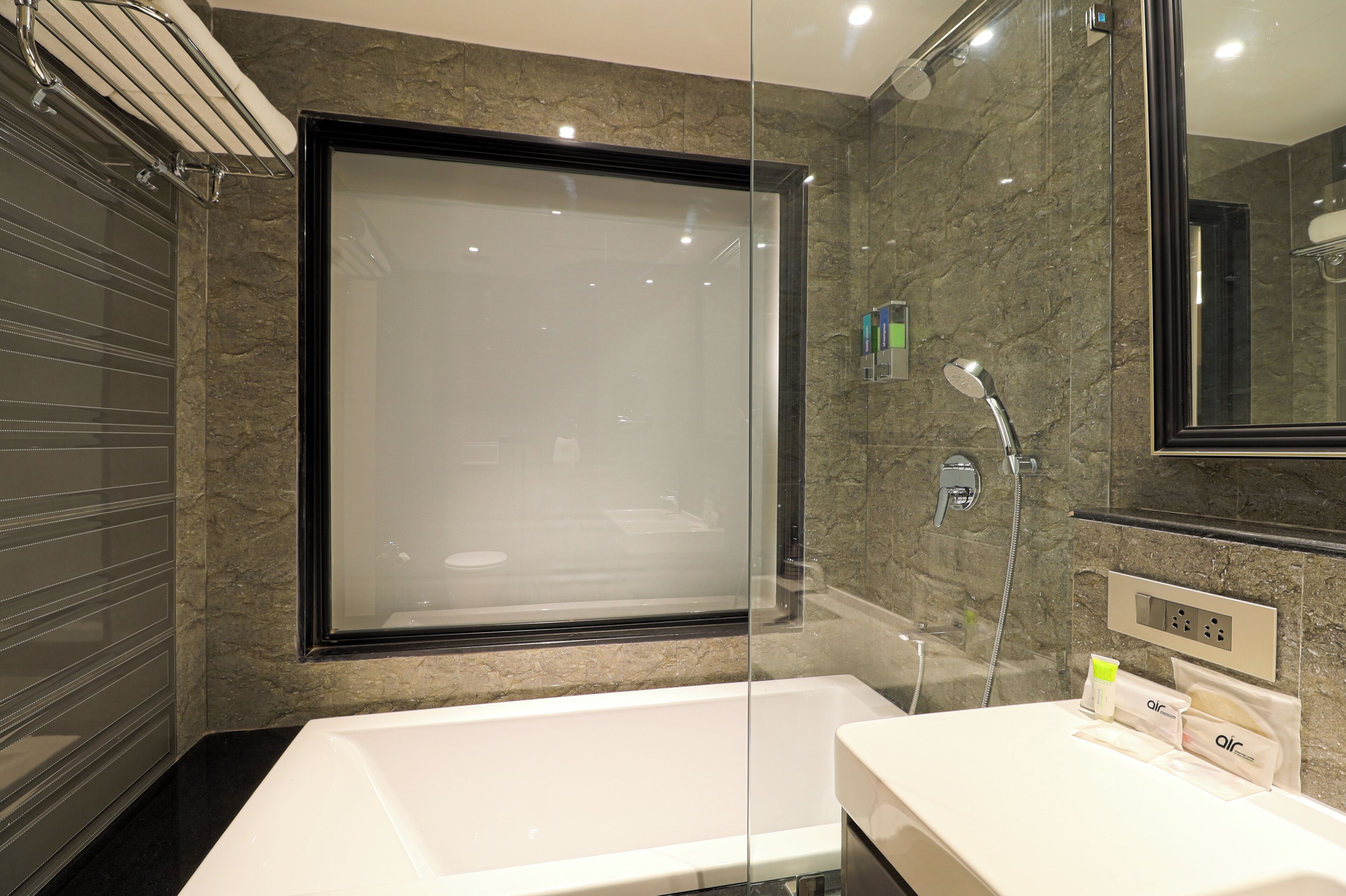 Une salle de bain moderne avec une douche à parois de verre, une baignoire blanche et un meuble-lavabo avec des articles de toilette.