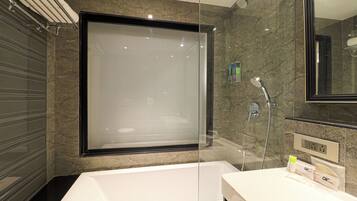 Un baño moderno con ducha envuelta en vidrio, una bañera blanca y un tocador con artículos de aseo.