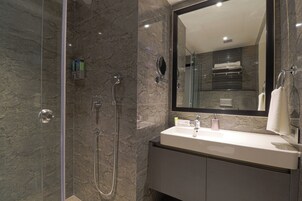 A modern bathroom with a glass-enclosed shower, a marble sink, and a large mirror.