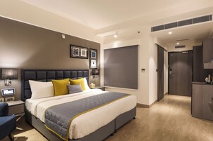 A modern bedroom with a large bed, bedside tables, a desk, and a wardrobe.