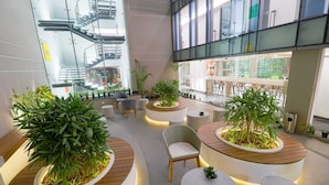 A modern indoor space with seating areas, potted plants, and a staircase. - AIR by Ahuja Residences (Gurugram)