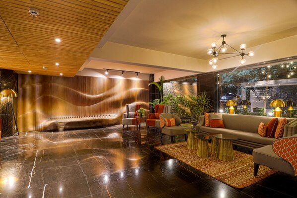 A modern lobby with a wooden ceiling, a large seating area, and a view of the outside. - AIR by Ahuja Residences (Gurugram)