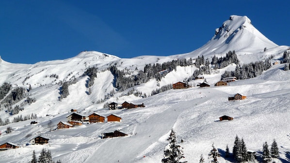 A snow-covered mountain with wooden chalets and ski slopes.