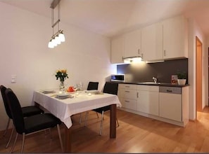 A modern kitchen with white cabinets, a dining table set for two, and a microwave.