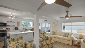 A spacious living area with a sofa, chairs, a dining table, and a kitchen area with a microwave and stove. - Vitamin Sea - Gulf Front, Pet Friendly, Wifi, Sleeps 6 (Port St Joe)