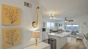 A modern kitchen with a central island, a dining area with a view, and artwork on the walls. - Vitamin Sea - Gulf Front, Pet Friendly, Wifi, Sleeps 6 (Port St Joe)
