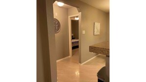 A hallway with a tiled floor, a door leading to another room, and a countertop with a sink. - Cozy 3BR 2BA Longhorn Creek Retreat Near JW Marriott with Fenced Yard (San Antonio)