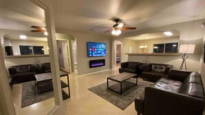 A spacious living room with a flat-screen TV, leather sofas, a coffee table, and a ceiling fan. - Cozy 3BR 2BA Longhorn Creek Retreat Near JW Marriott with Fenced Yard (San Antonio)
